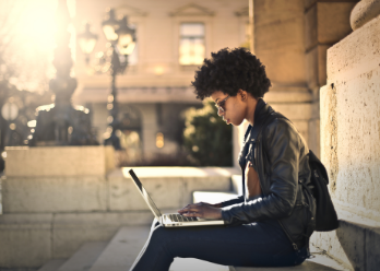 Woman sitting on campus looking at laptop