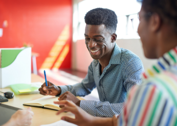 Man smiling while working with colleague
