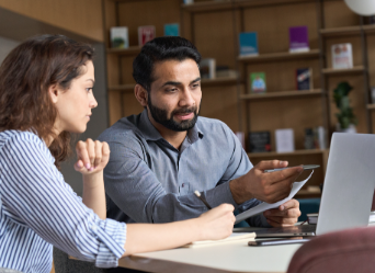 Multiethnic man and woman collaborating over papers and laptop