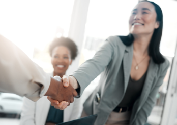 Asian woman shaking hands with out-of-frame man