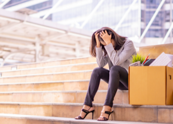 Woman sitting on stairs, head in hand, next to a box