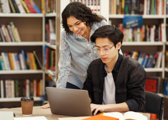 Advisor working with college student in library
