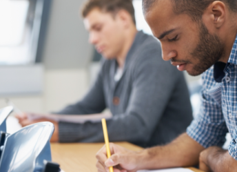 Male student taking exam in lecture hall