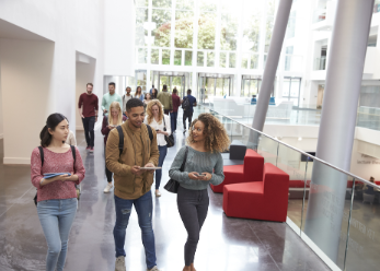 Diverse college students walking in modern campus buidling